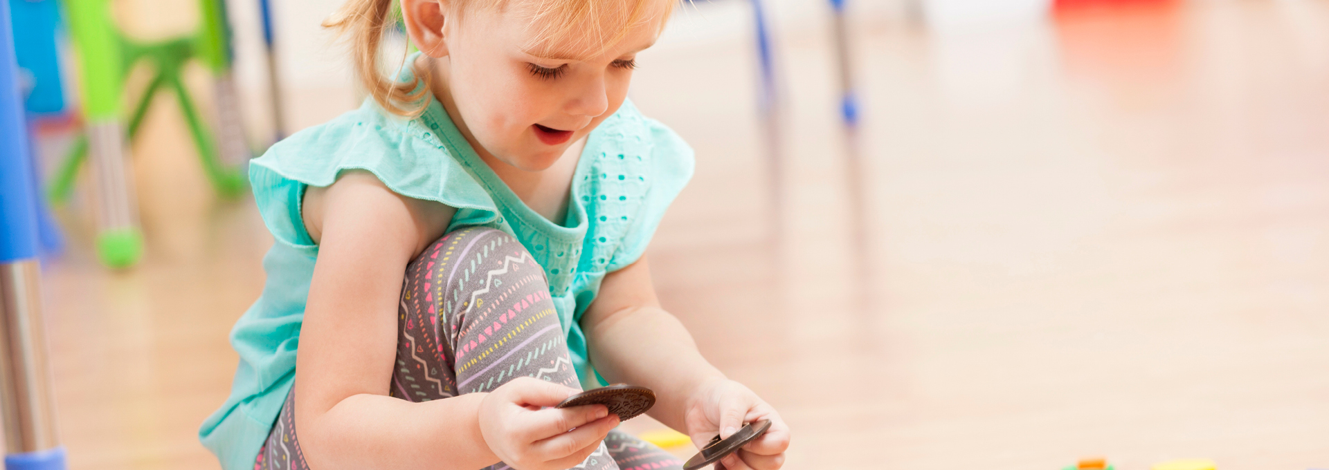 Ein kleines Mädchen sitzt spielt mit Bauklötzen, Viele Bauklötze liegen auf dem Boden