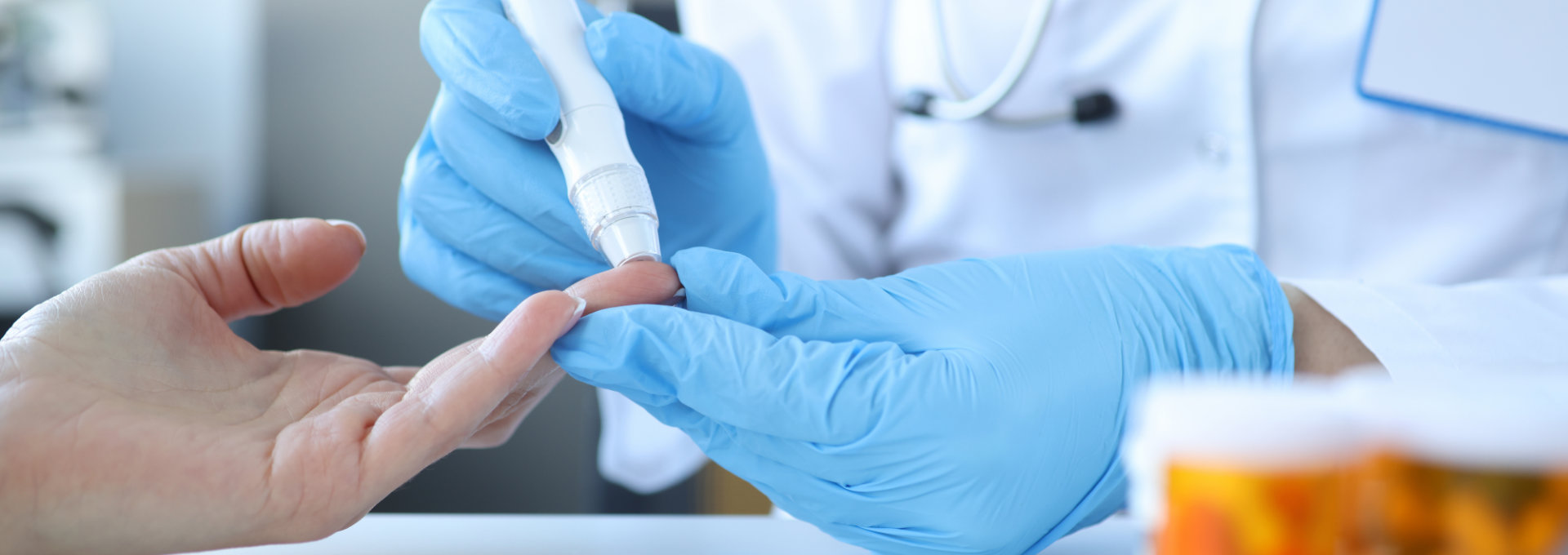 Doktor untersucht den Blutzucker am Finger eines Patienten.