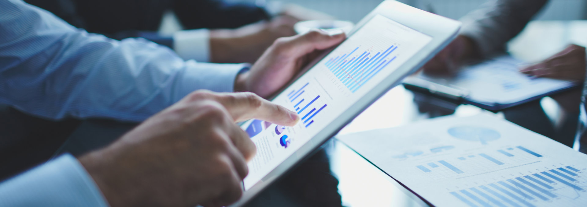 Eine Hand tippt auf ein Tablet, welches Statistiken zeigt