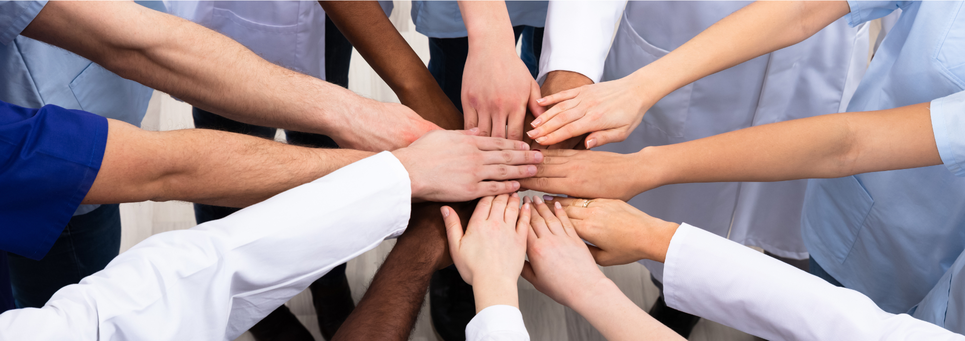 Ärzteteam legt die Hände aufeinander als Zeichen von Zusammenhalt