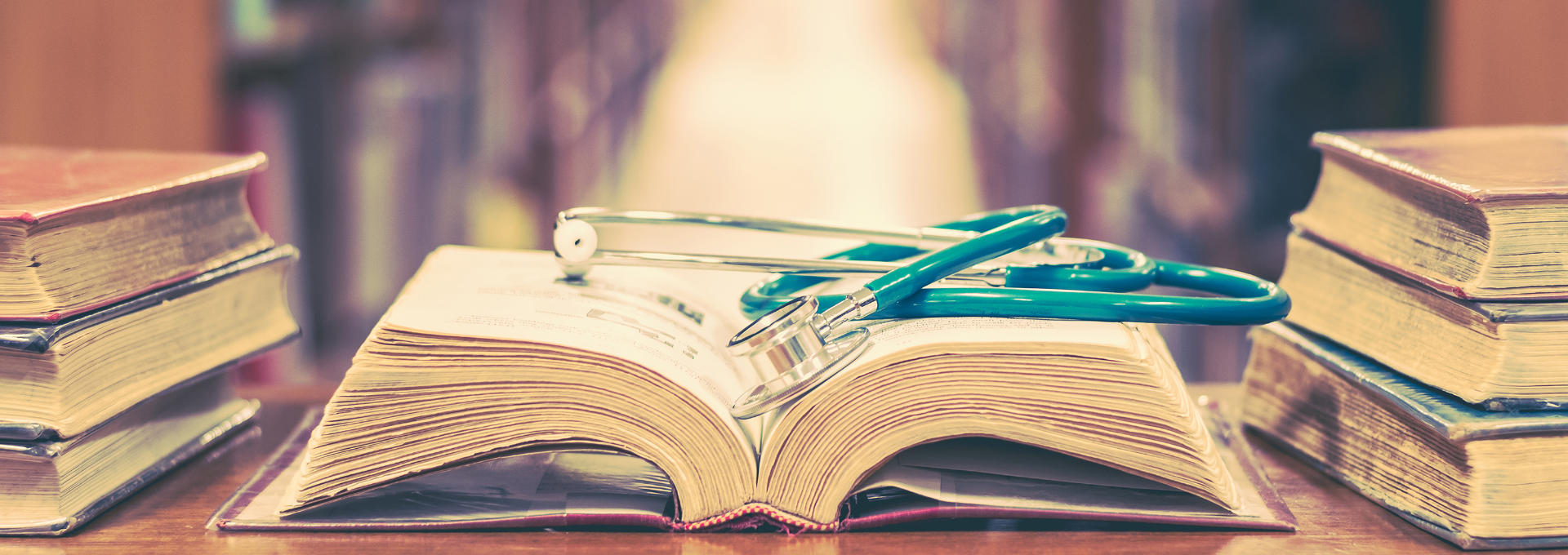 Ein Stethoskop liegt auf einem alten, aufgeschlagenen Buch.