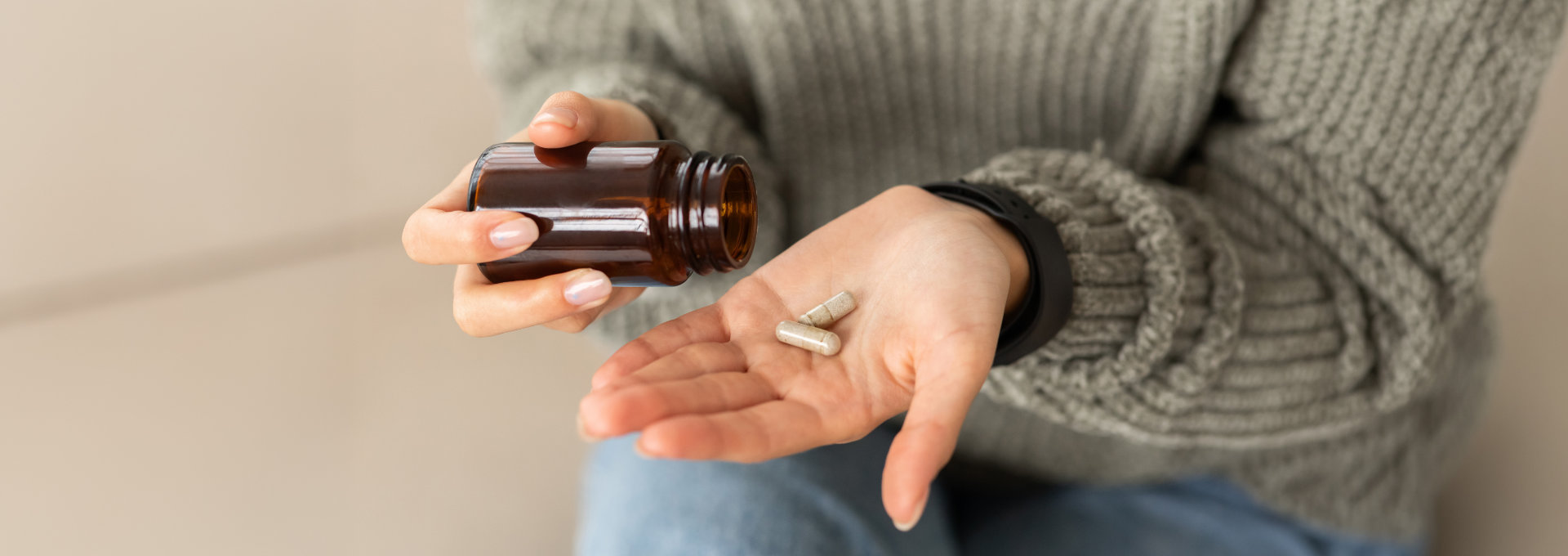 Eine junge Frau kippt sich Tabletten auf die Handfläche.
