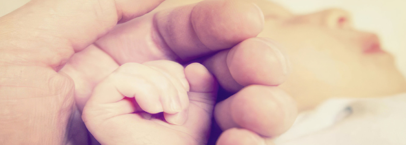 eine Nahaufnahme der Hand eines Babys und einer Erwachsenenhand